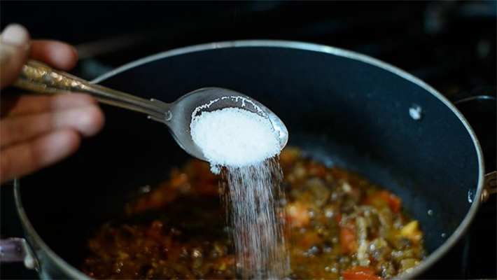 someone adding salt to food