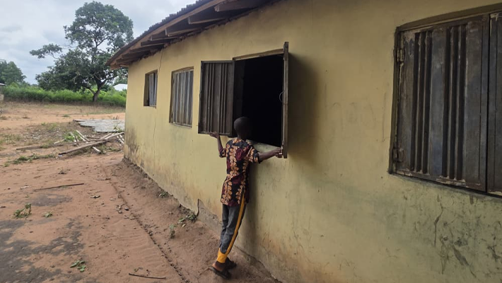 Sodiq Farouq stands in front of his classroom window, the same one he jumped through to escape abduction on May 15.