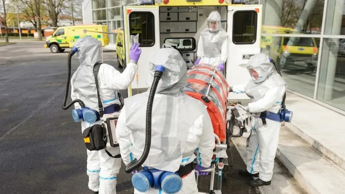 Health workers in protective gear wheel a patient into an ambulance. Photo: Used to illustrate the story